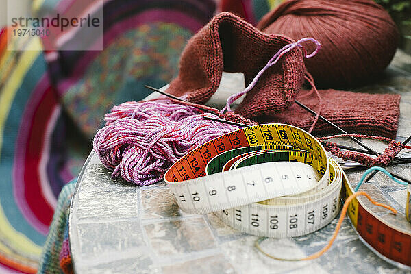 Maßband mit Wolle und Stricknadeln auf dem Tisch