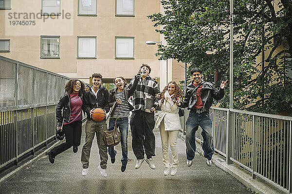 Fröhliche Teenager-Freunde springen gemeinsam auf dem Fußweg