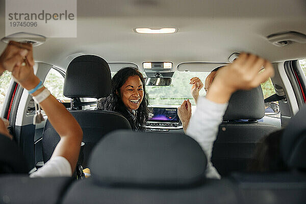 Glückliche Eltern haben Spaß mit ihren Töchtern im Auto während der Autofahrt
