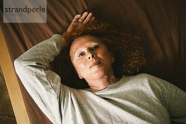 Blick aus der Vogelperspektive auf eine nachdenkliche ältere Frau  die zu Hause im Bett liegt