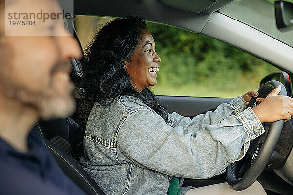 Seitenansicht einer glücklichen Frau in Jeansjacke und Autofahren