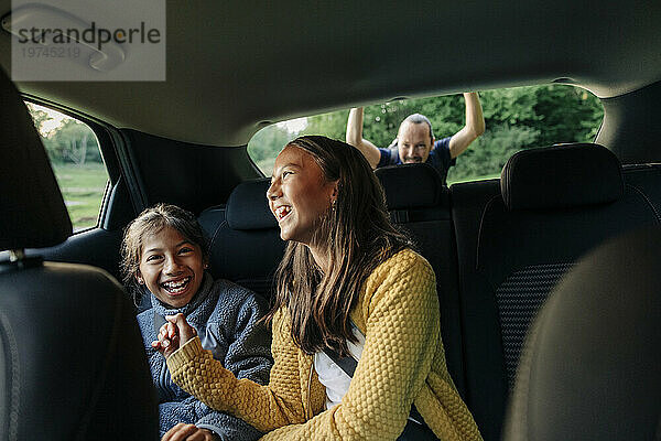 Fröhliche Schwestern lachen  während sie im Auto sitzen