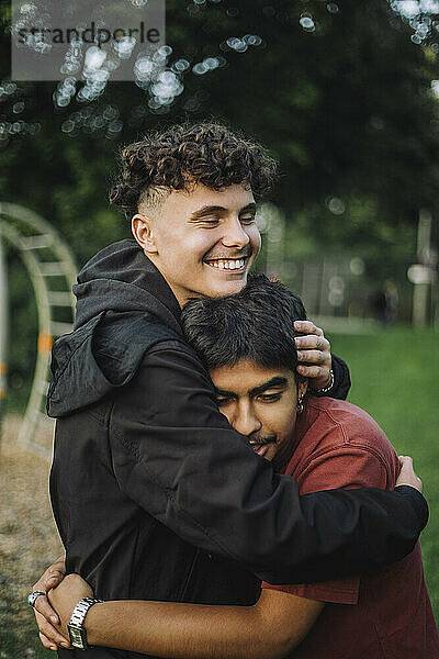 Glücklicher Junge umarmt männlichen Teenager-Freund im Park