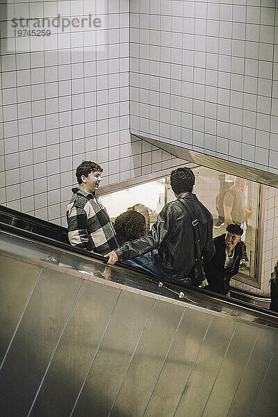 Glückliche männliche und weibliche Teenager-Freunde  die von der Rolltreppe im Einkaufszentrum herunterkommen