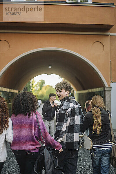 Lächelnder Teenager  der beim Spaziergang mit Freunden über die Schulter schaut