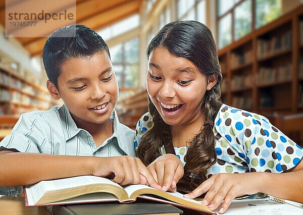 Zwei hispanische Schüler haben Spaß beim Lernen in einer Schulbibliothek