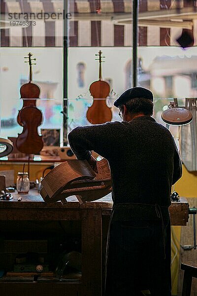 Senior Experte Geigenbauer Geigenbauer schnitzen Skulptur Meißel Rippen eines neuen klassischen Modells Cello in der Werkstatt Cremona Italien  selektiver Fokus  Bokeh