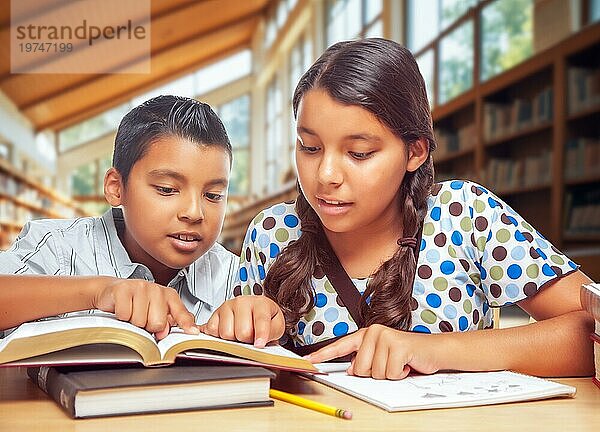 Zwei hispanische Schüler studieren mit ihren Büchern in einer Bibliothek