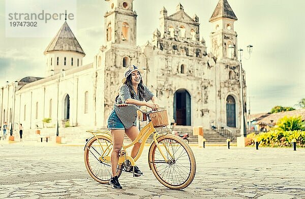 Lebensstil eines glücklichen Mädchens mit Hut auf dem Fahrrad auf der Straße. Granada  Nicaragua. Glückliches Mädchen mit Hut auf einem Fahrrad bei Sonnenuntergang. Tourismus und Reisen Konzept