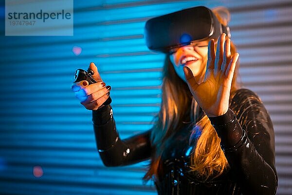 Lächelnde Frau  die mit einer Virtual Reality Brille bei Nacht spielt