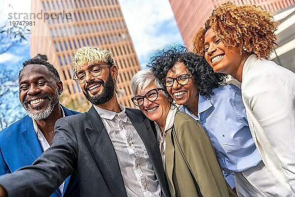 Niedriger Winkel Seitenansicht von multiethnischen Geschäftsleuten lächelnd und nehmen ein Selfie im Freien