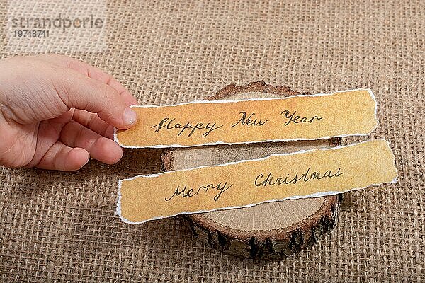 Frohes neues Jahr  Frohe Weihnachten  geschriebenes Papier auf Holz