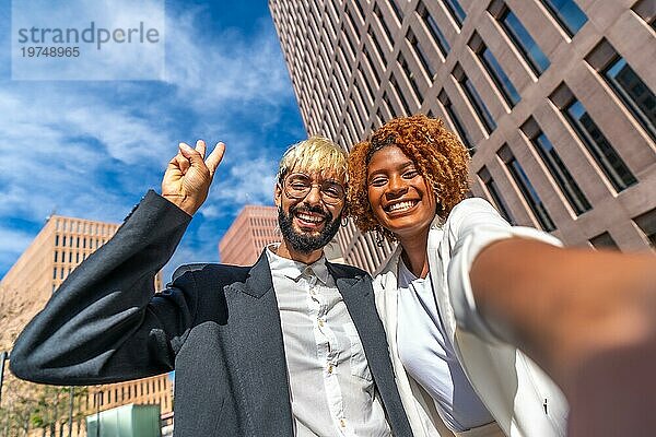 Frontalaufnahme von zwei jungen multiethnischen Geschäftsleuten  die ein Selfie im Freien machen
