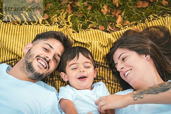 Draufsicht auf eine glückliche Familie  die lächelnd im Gras liegt