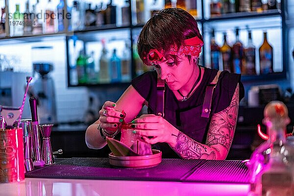 Konzentrierte junge Barkeeperin dekoriert einen Cocktail in der Theke eines Nachtclubs