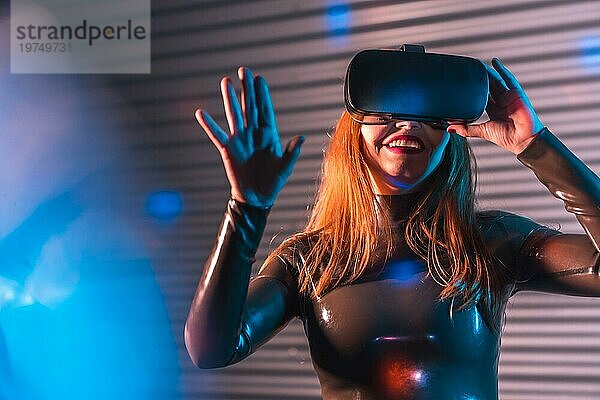 Glückliche futuristische Frau  die mit einer VR Brille in die metaverse Realität eintaucht