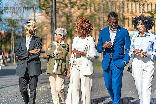 Elegante multikulturelle Geschäftsleute unterhalten sich entspannt bei einem Spaziergang durch die Stadt