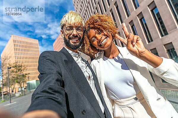 Niedriger Blickwinkel und Frontalansicht Foto von einem Geschäftsmann und Geschäftsfrau sprechen ein Selfie lächelnd und Gesten Erfolg im Freien