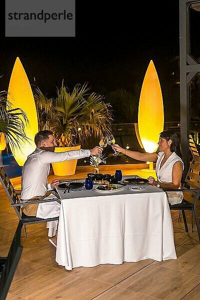 Vertikales Foto eines romantischen Paares  das bei einem luxuriösen Abendessen im Freien anstößt