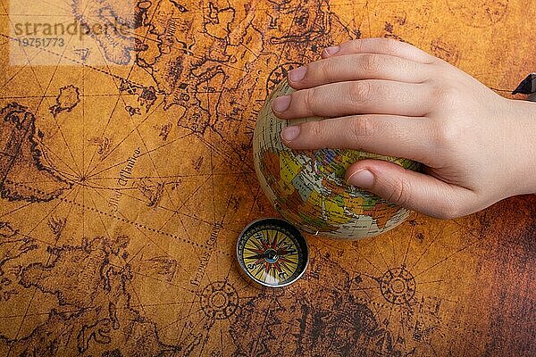 Kompass auf Karte neben einem Globus in der Hand