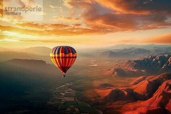 Eine bunte Heißluftballon schwebt in Himmel über einer Wüste Berglandschaft bei Sonnenuntergang mit orange und blaün Himmel im Hintergrund. Reise Reise Abenteuer Schönheit der Natur Konzept