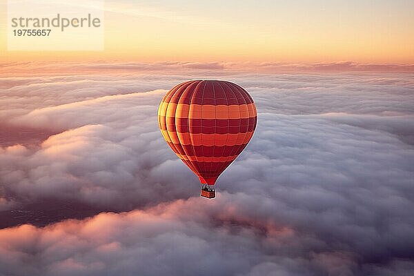 Bunte Heißluftballon schwebt über ein Meer von Wolken bei Sonnenuntergang bei Sonnenuntergang mit orange und blaün Himmel im Hintergrund. Reise Reise Abenteuer Schönheit der Natur Konzept