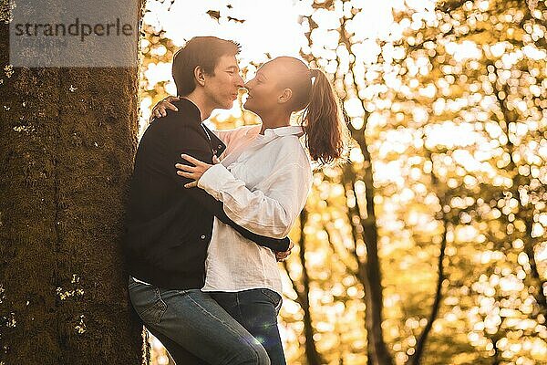 Sonnenstrahlen beleuchten ein sich küssendes Paar im Wald