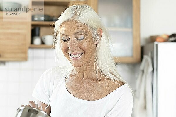 Ältere Frau mit langen Haaren kocht zu Hause in der Küche