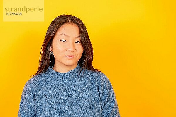 Studiofoto mit gelbem Hintergrund von einer chinesischen jungen Frau  die in die Kamera lächelt