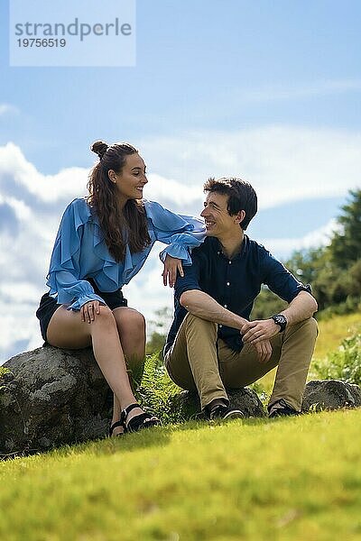 Paar verbringt Zeit in den Bergen zusammen sitzen auf einem Hügel und lächelnd