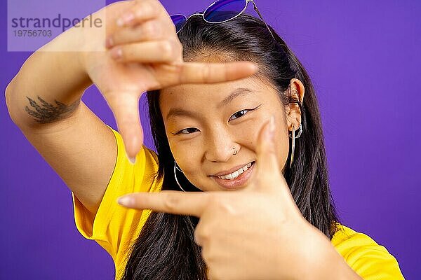 Studio Foto mit lila Hintergrund einer chinesischen Frau lächelnd und Framing mit Händen