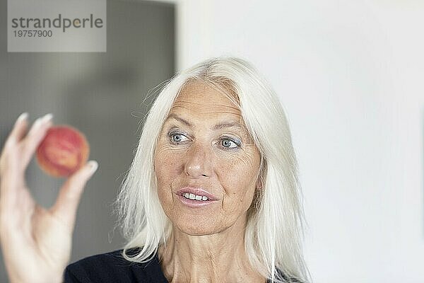 Ältere Frau mit langen Haaren hält roten Ball in der Hand