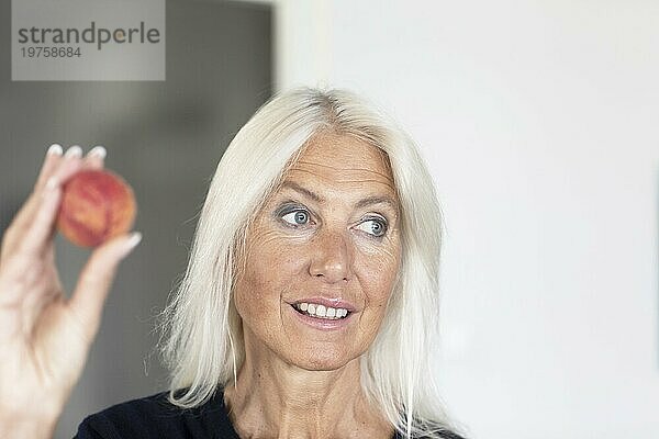 Ältere Frau mit langen Haaren hält roten Ball in der Hand