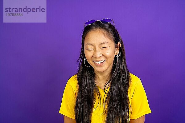 Studio Foto mit lila Hintergrund einer chinesischen Frau lachend mit geschlossenen Augen