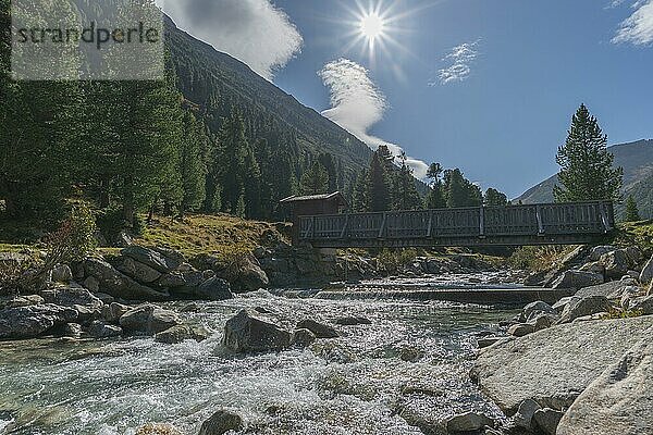 Holzbrücke über Zamser Bach im Tal Zamser Grund  Schlegeis  Wanderweg  Nadelwald  Felsen  Gegenlicht  blauer Himmel  Zillertaler Alpen  Tirol  Österreich  Europa