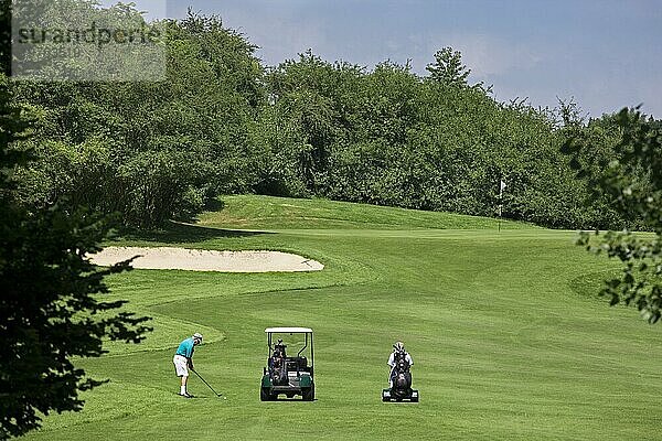 Rentner mit Golfwagen spielt Golf auf dem Fairway eines Golfplatzes in Europa