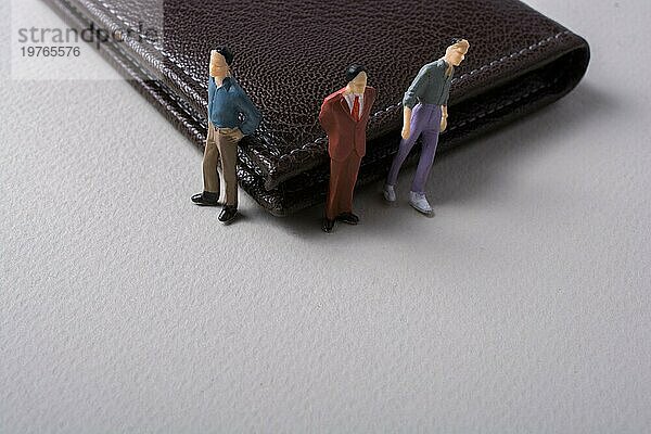 Winzige Figur von Männern Miniaturmodell neben einer Brieftasche