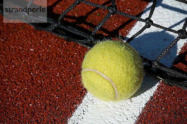 Tennisszene mit schwarzem Netz und Ball auf weißer Linie in Tiefwinkelansicht und selektivem Fokus