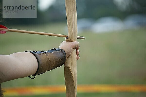 Mittelalterliche Bogenschützenhand in Großaufnahme mit Holzbogen und Pfeil