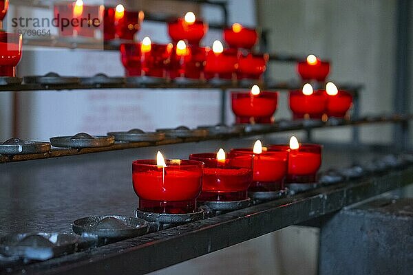 Brennende rote Gebetskerzen in einer katholischen Kirche auf einem Kerzenständer. Selektiver Fokus