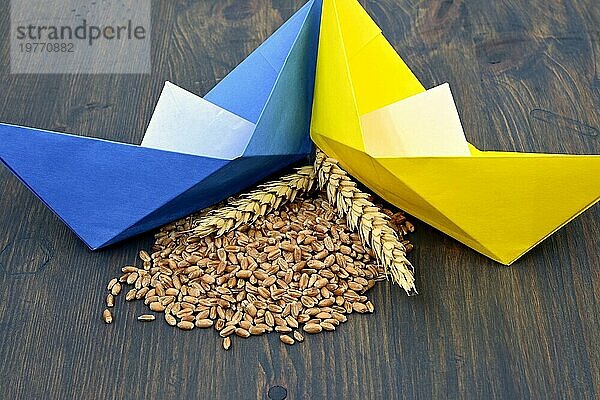 Ukrainische Flagge Farben Origamiboote und Weizen Getreide mit reifen Weizenähren. Konzept der Getreide schwimmende Probleme