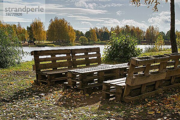 Gartenmöbel aus Holzpaletten am Ufer eines ruhigen Sees im Herbst