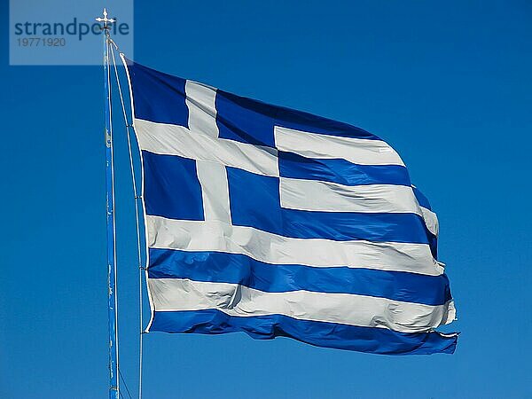 Die griechische Nationalflagge am Fahnenmast entwickelt sich im Wind gegen den blaün Himmel