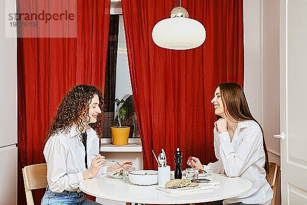 Zwei Freunde  die zu Hause zusammen essen und sich unterhalten