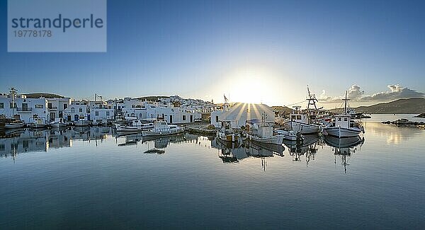 Fischerboote im Hafen von Naoussa bei Sonnenuntergang  spiegeln sich im Meer  Sonnenstern  Weiße kykladische Häuser  Naoussa  Paros  Kykladen  Griechenland  Europa