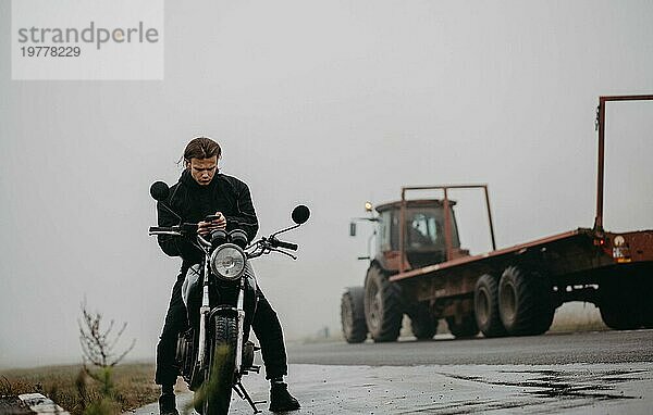 Motorradfahrer Männchen Biker auf einer nebligen Straße mit einem Motorrad im Herbst bei regnerischem Wetter  das Konzept der Ausrüstung für einen Motorradfahrer