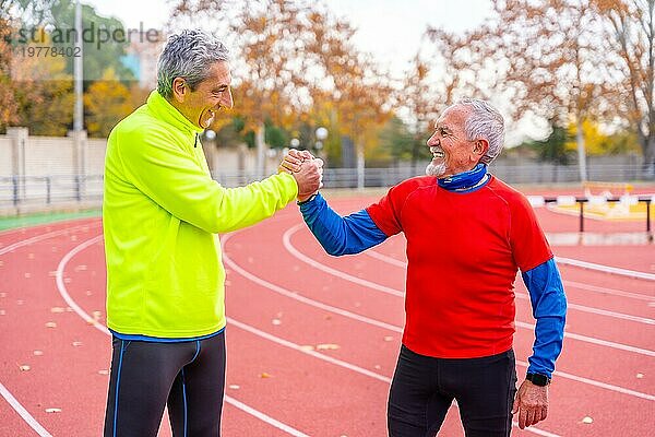 Ältere Sportfreunde schütteln sich nach einem Winterlauf im Freien stolz die Hände