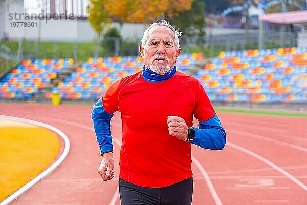 Porträt eines alten Mannes in Frontalansicht  der in einer Leichtathletikbahn läuft