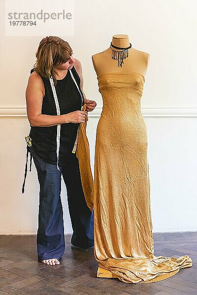 Ein Modedesigner heftet ausgeschnittene Stoffstücke an ein Mannequin