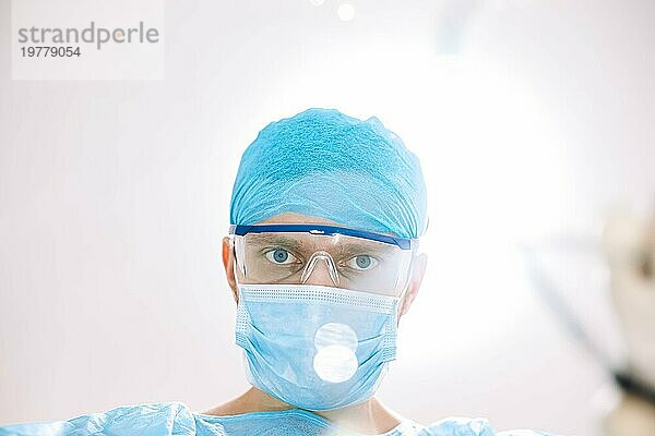 Chirurgischer Arzt im Operationssaal mit Blick in die Kamera